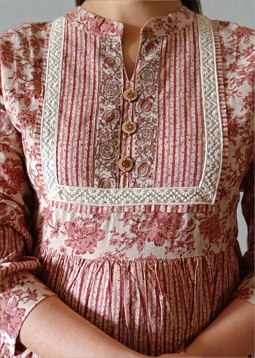 Woman wearing a floral stripe dress with lace yoke detal against a plain background