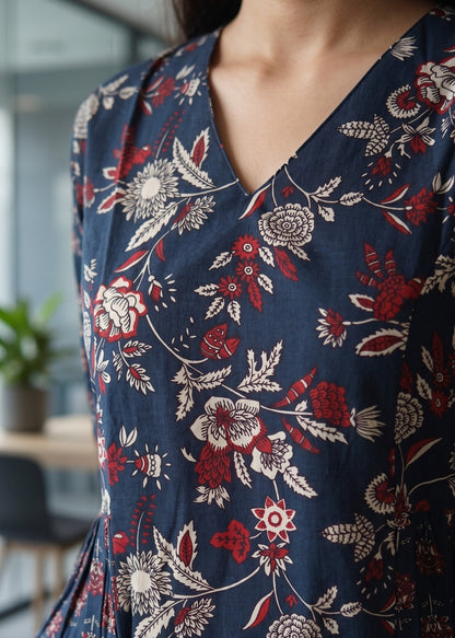 A close-up of a person wearing a navy blue V-neck short kurti with a red and cream floral pattern, paired with blue jeans.