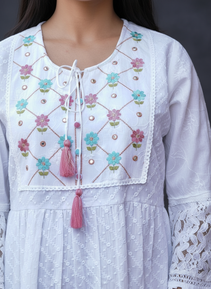 White embroidered dress with floral patterns and tassels on a blurred background