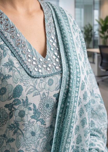 A close-up of a person wearing a light blue and white printed ethnic kurta suit set outfit with a matching dupatta, featuring a V-neckline with silver mirror work embroidery.