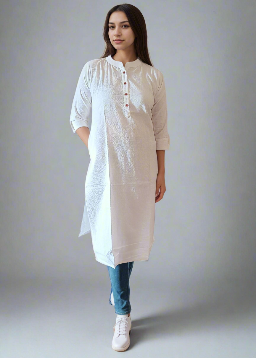 Woman wearing a white kurta with blue jeans against a plain background