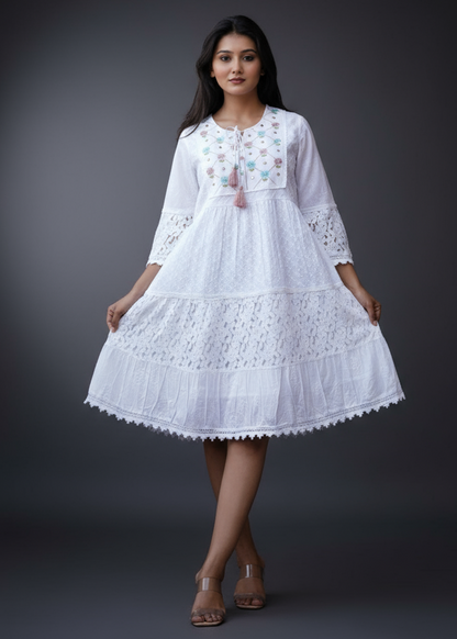 Woman wearing a white embroidered dress standing outdoors with architectural elements in the background