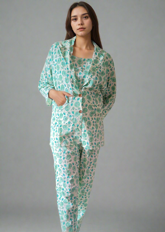 Woman wearing a green floral pajama set with a jacket against a plain background