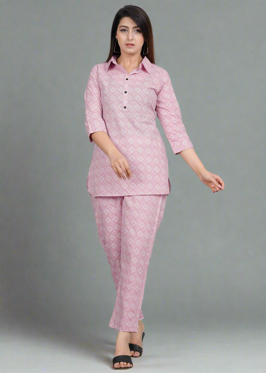 Woman wearing a pink traditional bandhani outfit with a pattern on a gray background