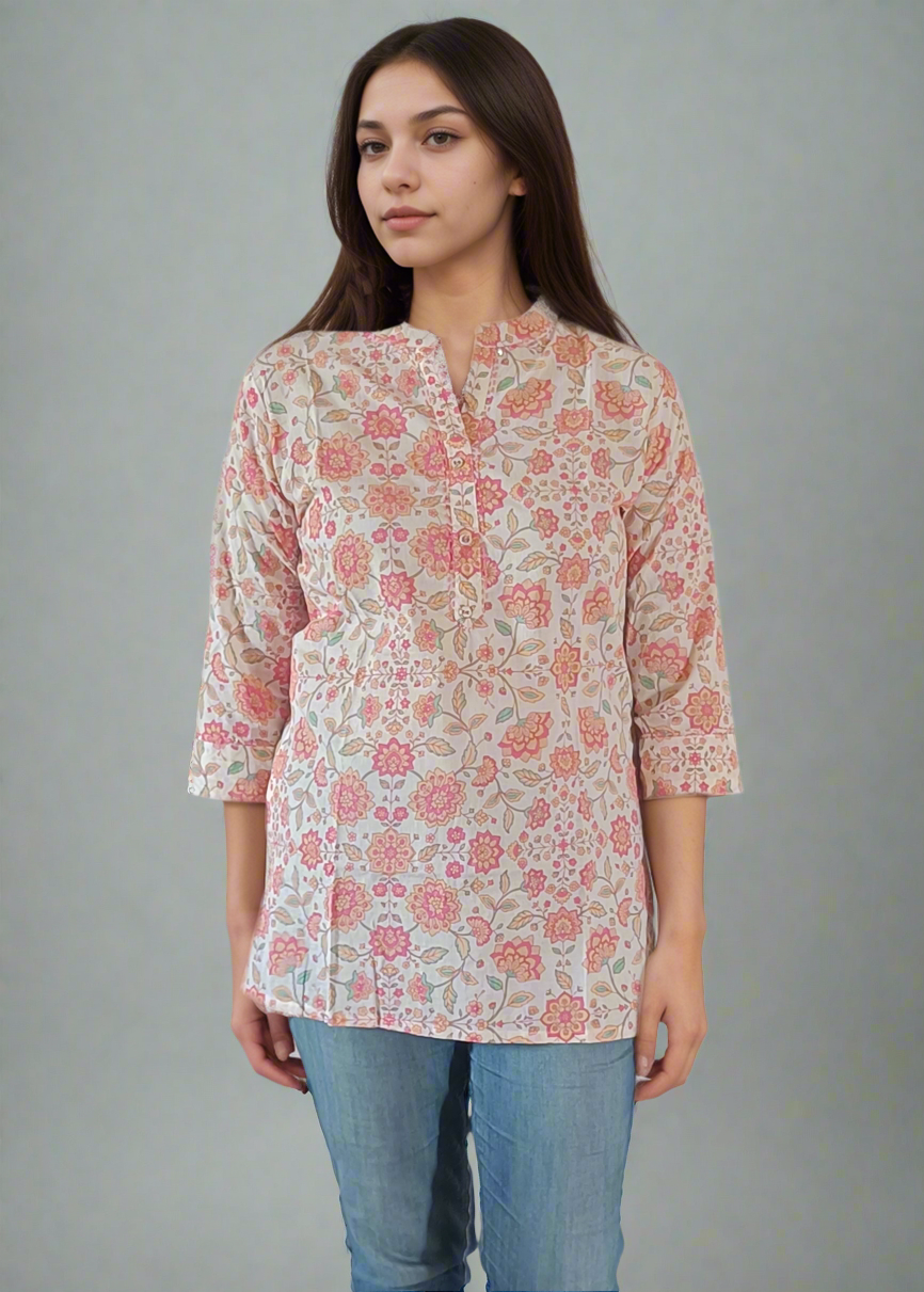 Woman wearing a floral tunic top blouse and blue jeans on a plain background