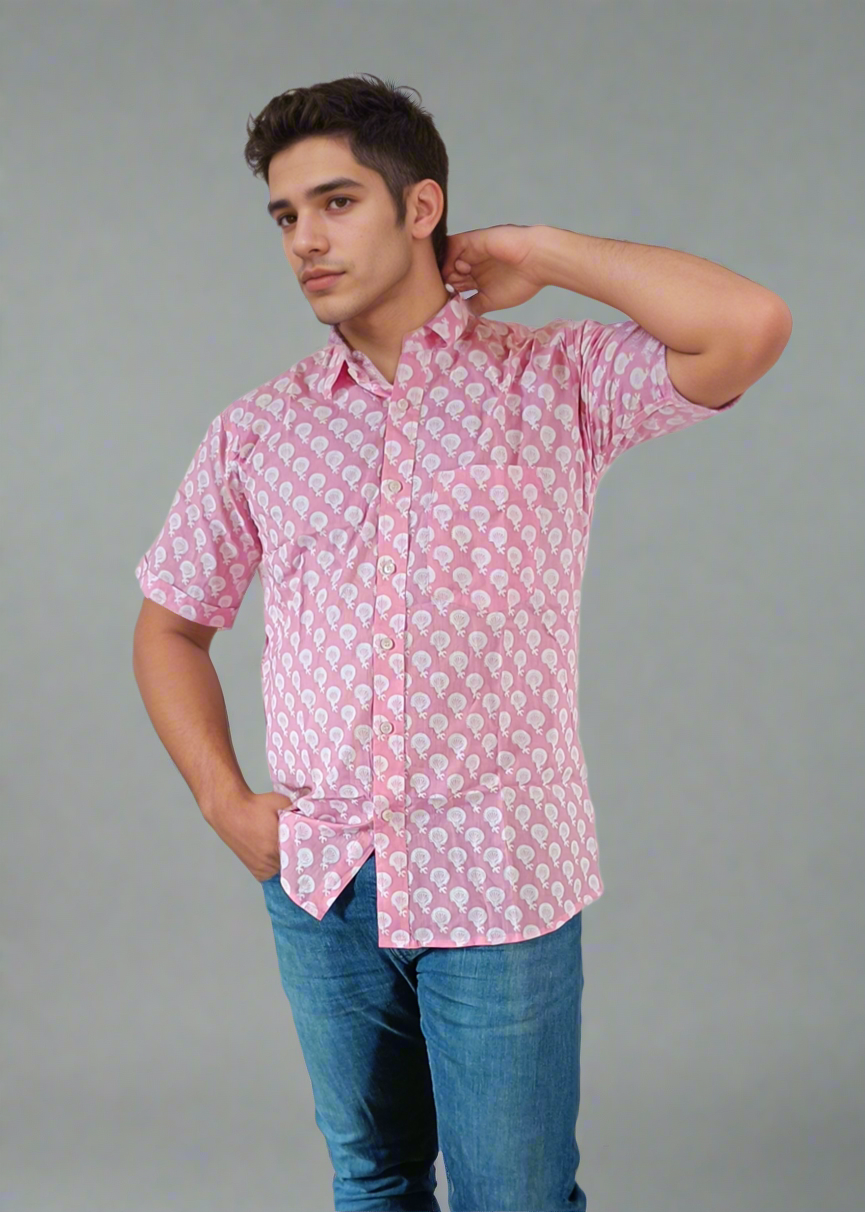 Man wearing a pink patterned shirt and blue jeans on a plain background