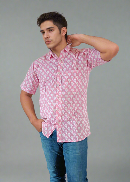Man wearing a pink patterned shirt and blue jeans on a plain background