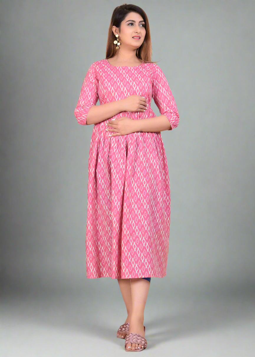 Woman wearing a pink patterned maternity dress standing on a beige background