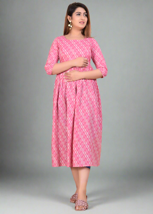 Woman wearing a pink patterned maternity dress standing on a beige background