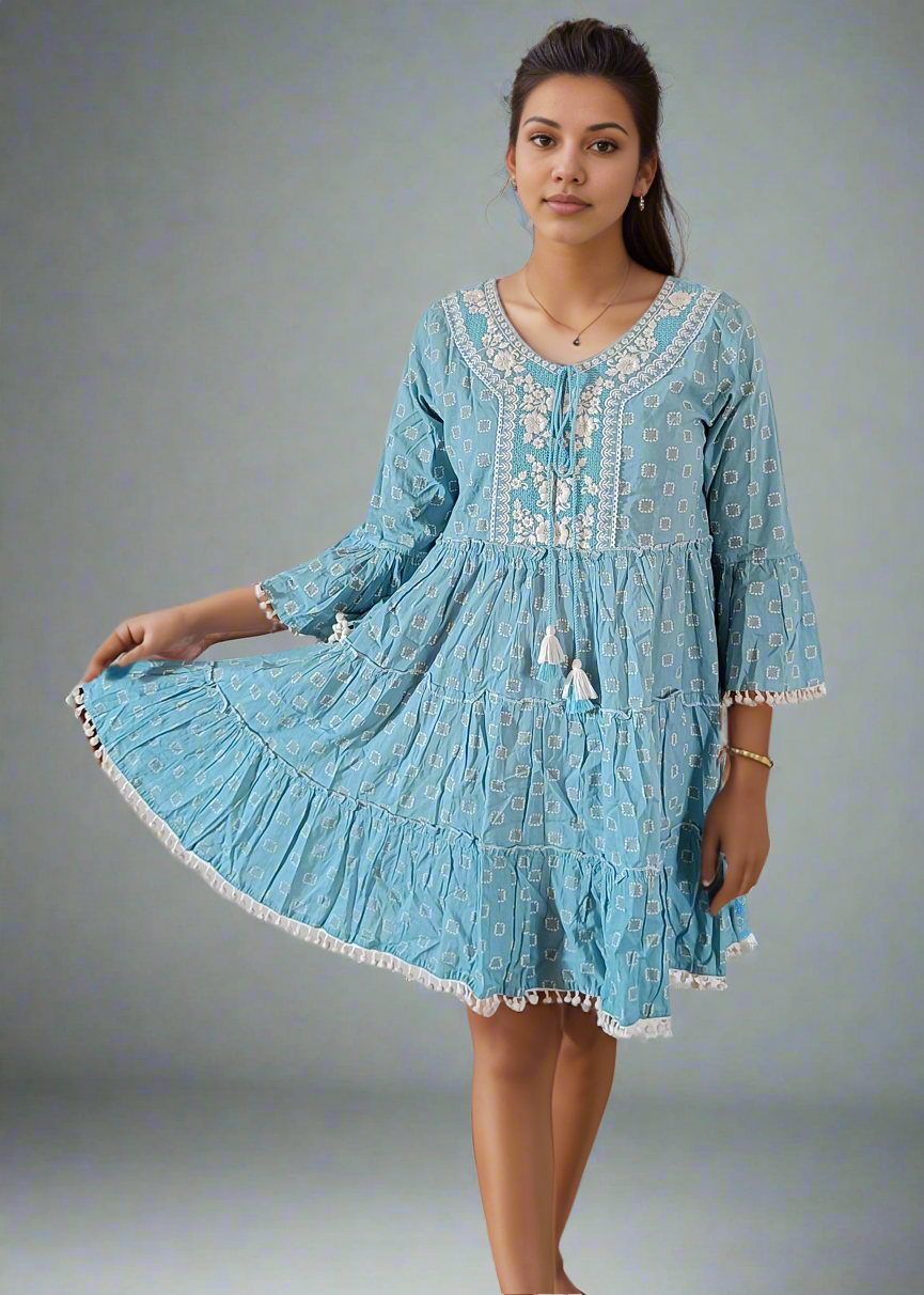 Woman wearing a light blue dress with white embroidery on a gray background