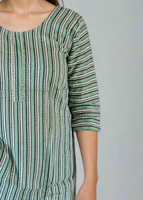 Woman wearing a green striped shirt and blue jeans against a plain background