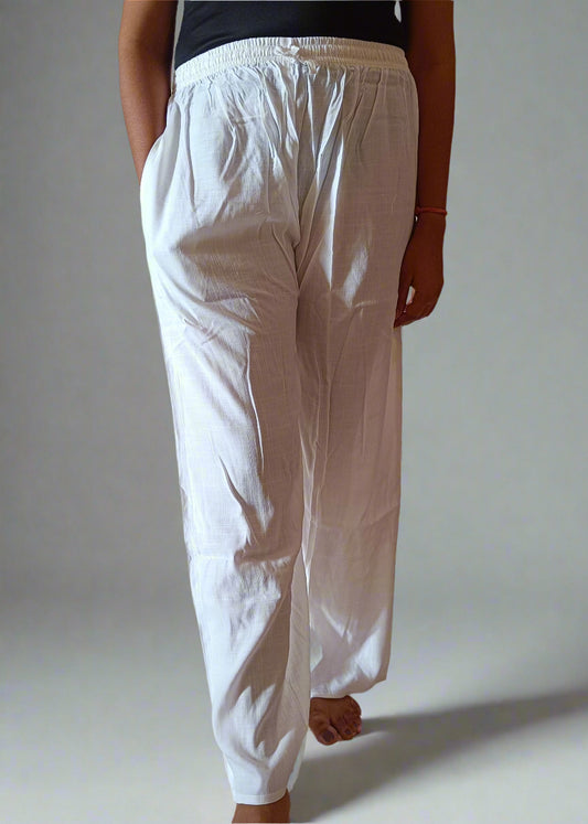Person wearing a black top and white pants standing indoors on a tiled floor.