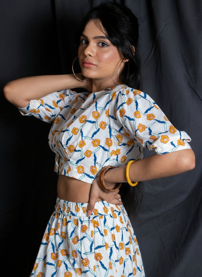 Woman wearing a white blouse with orange floral patterns against a dark background