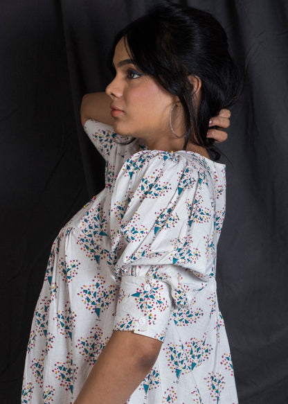 Woman wearing a white floral dress showcasing the puffed sleeve detail and cuff