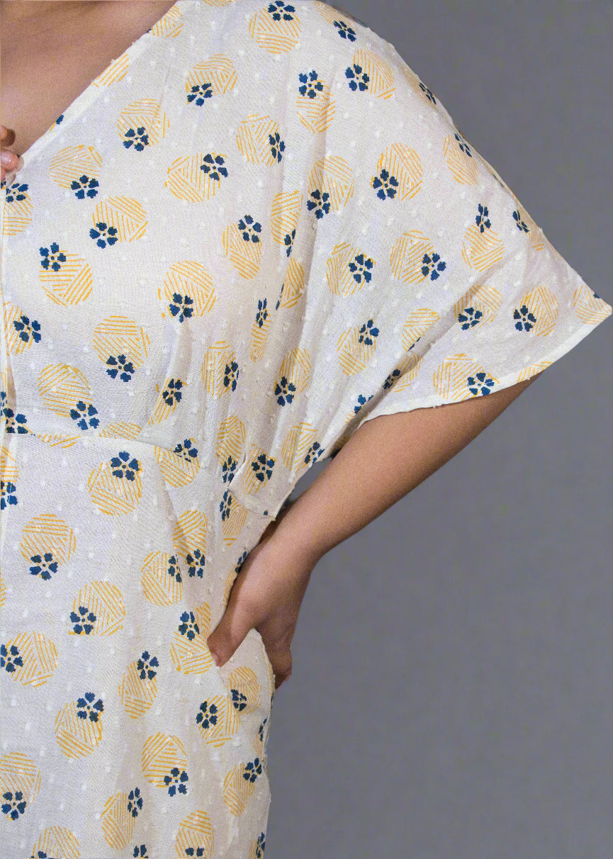 Person wearing a white garment with yellow floral patterns and a black garment.