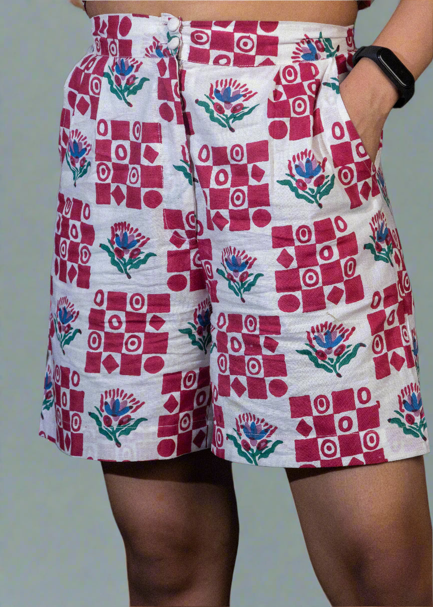 Person wearing a patterned shorts with red and white design on a dark background