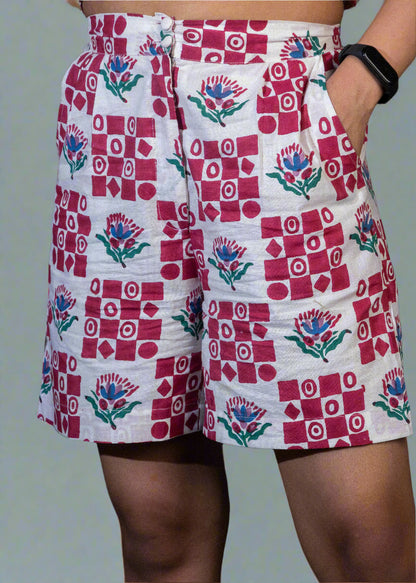 Person wearing a patterned shorts with red and white design on a dark background
