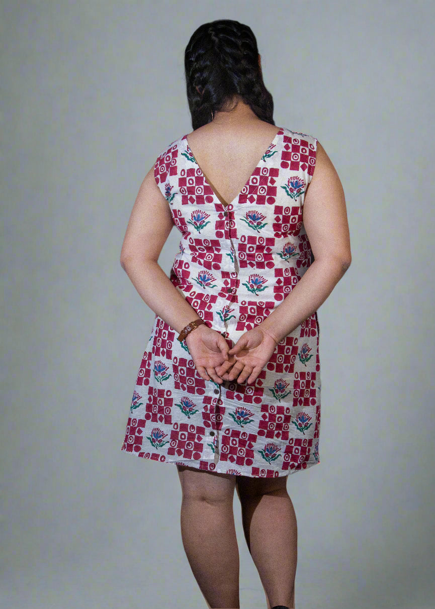 Person wearing a patterned dress with a dark curtain background