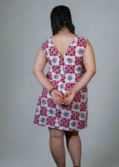 Person wearing a patterned dress with a dark curtain background