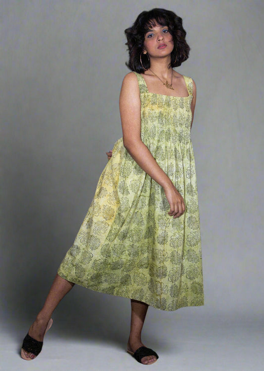 Woman wearing a green floral tropical batik dress against a plain background