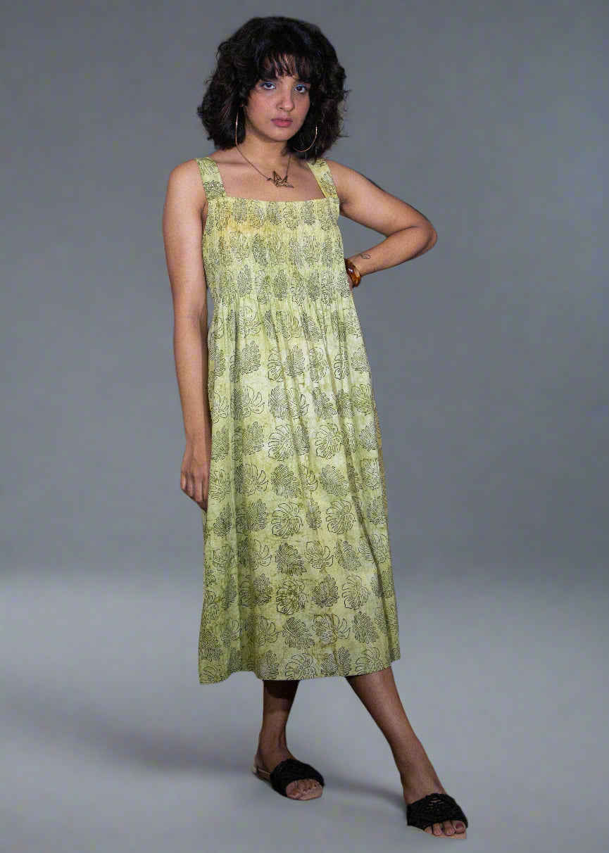 Woman wearing a green floral tropical batik dress against a plain background