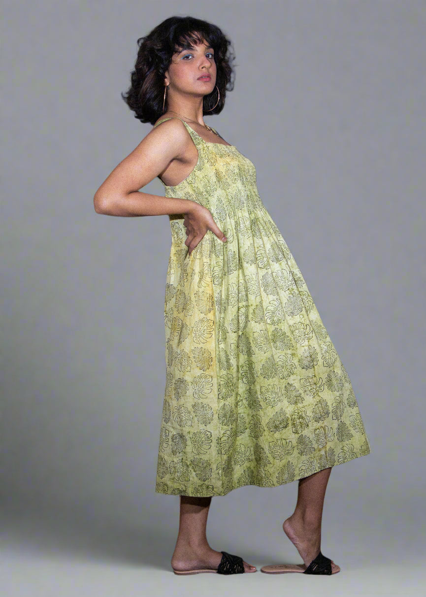 Woman wearing a green floral tropical batik dress against a plain background
