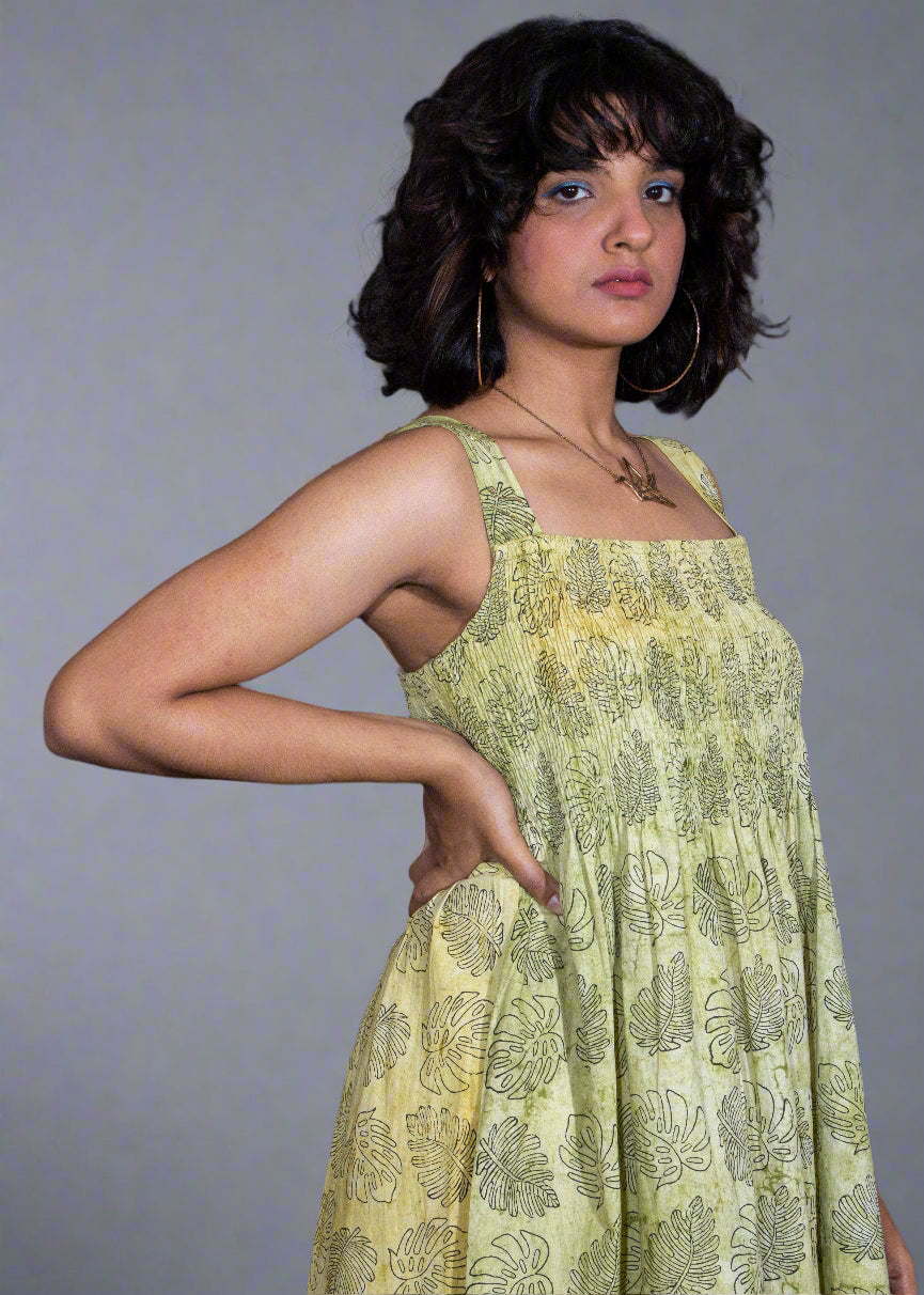 Woman wearing a green floral tropical batik dress against a plain background