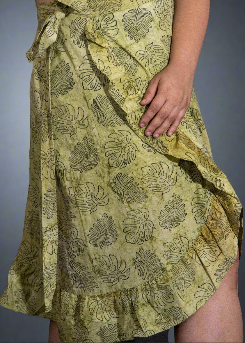 Green leaf-patterned wrap skirt worn by a person on a black background