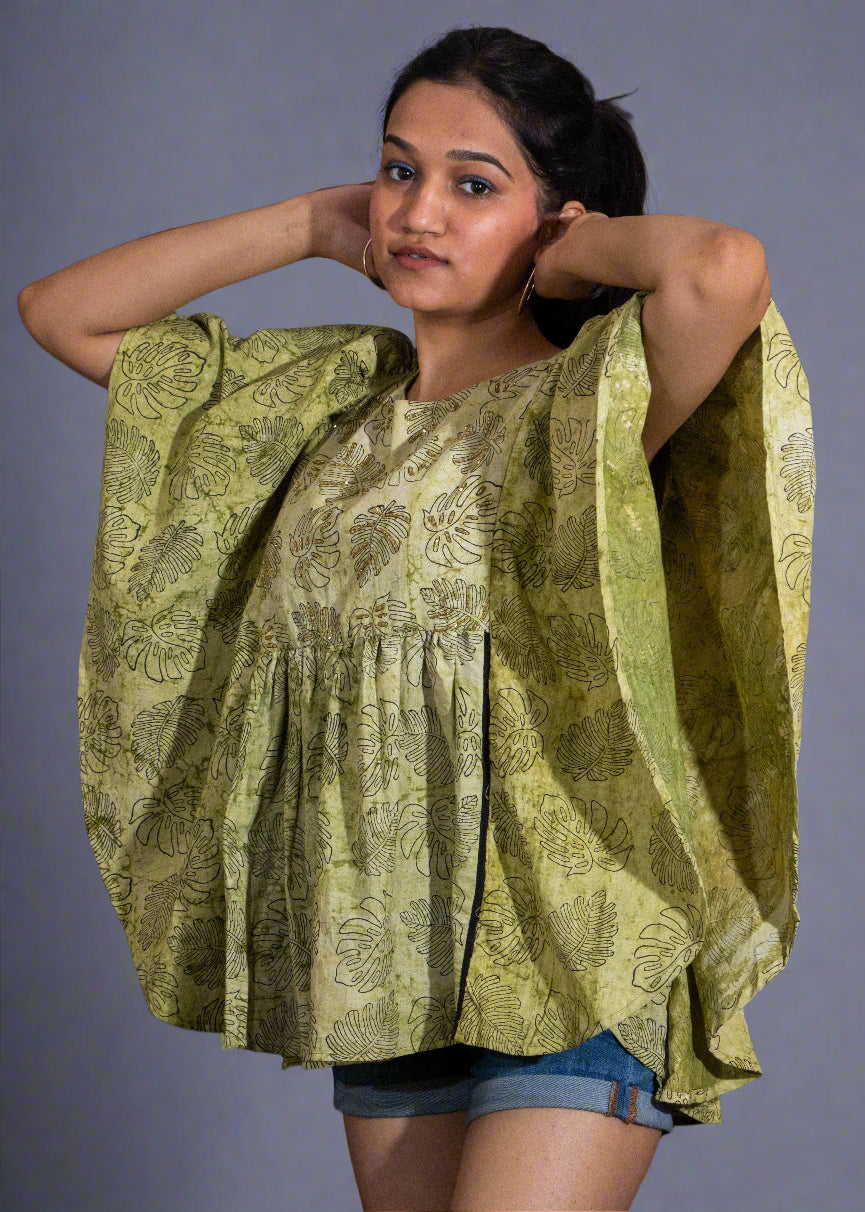 Woman wearing a green patterned blouse against a black background