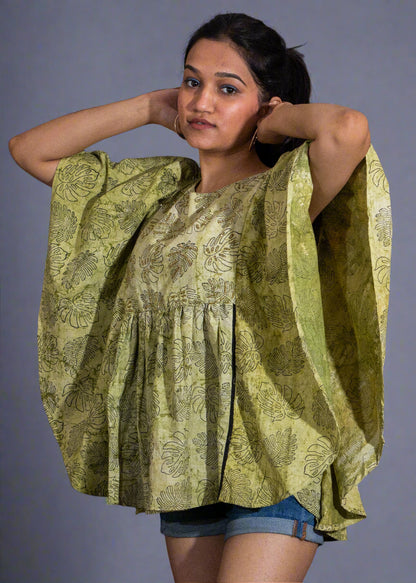 Woman wearing a green patterned blouse against a black background
