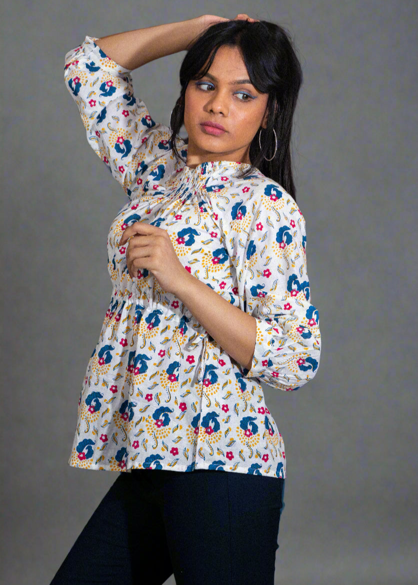 Woman wearing a hand block floral paisley blouse against a dark background