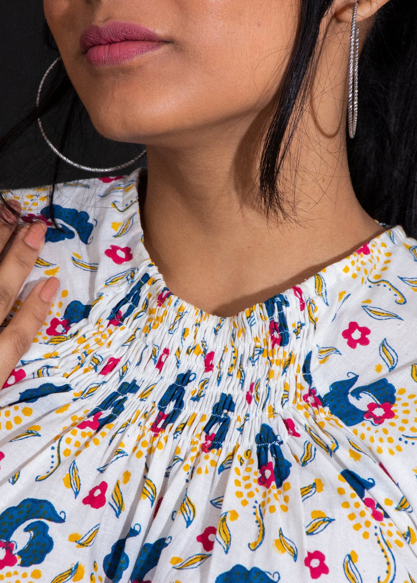 Woman wearing a floral smocking blouse with a dark background