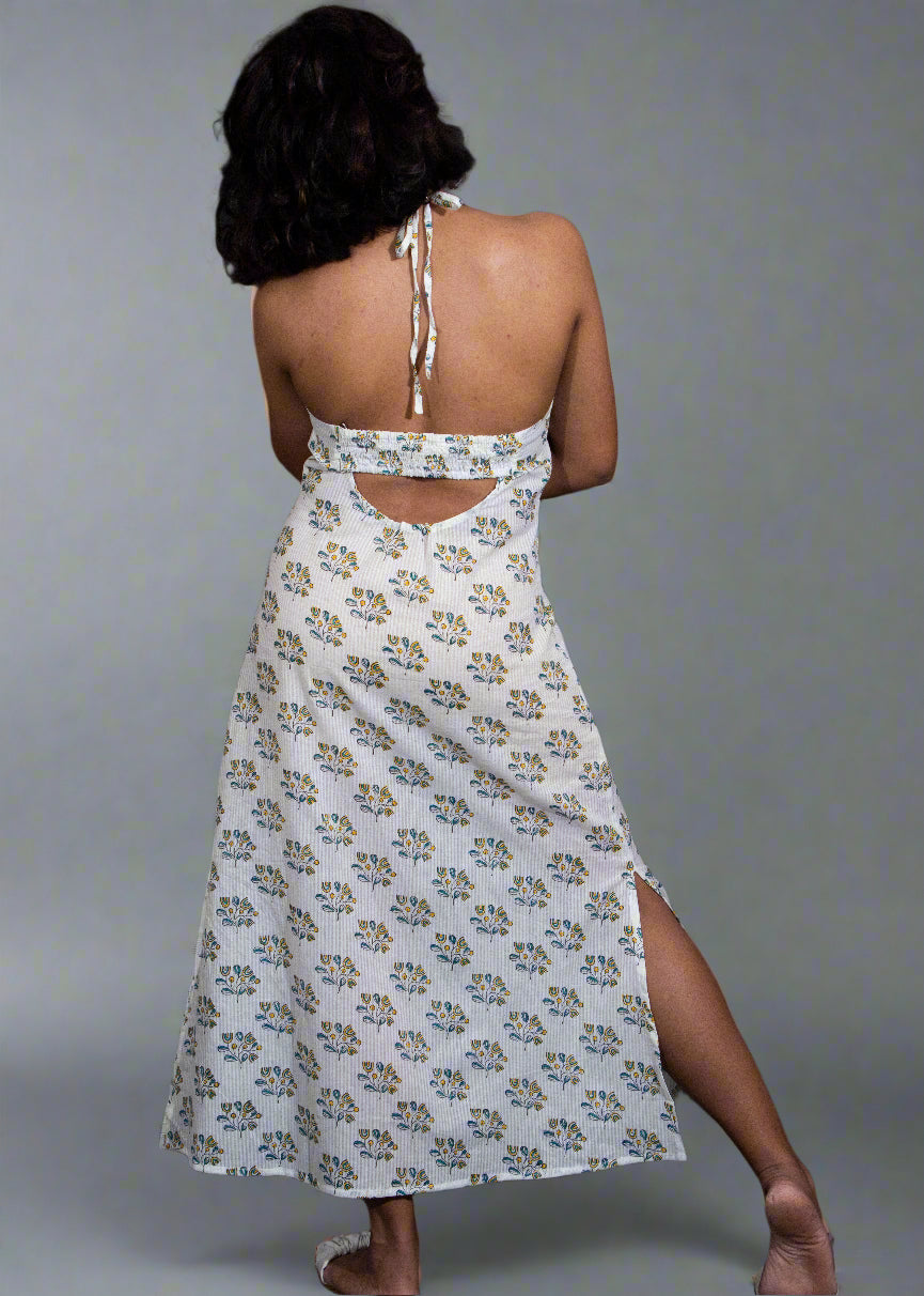 Woman wearing a white floral dress with cut-out back and slit skirt against a black background