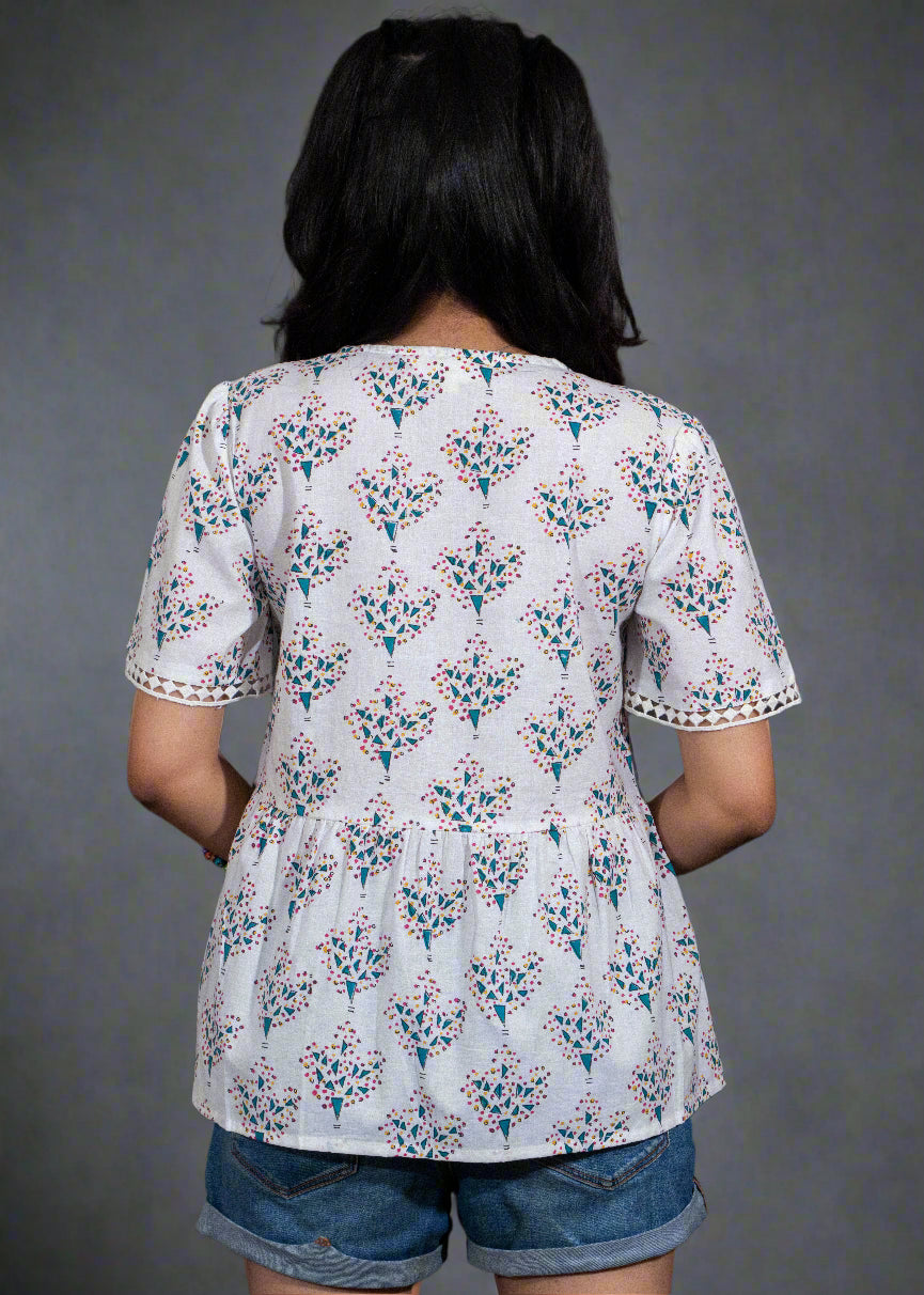 Person wearing a white floral blouse with a black background