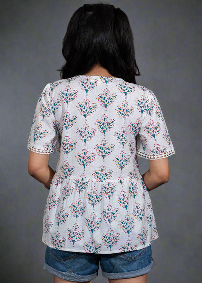 Person wearing a white floral blouse with a black background