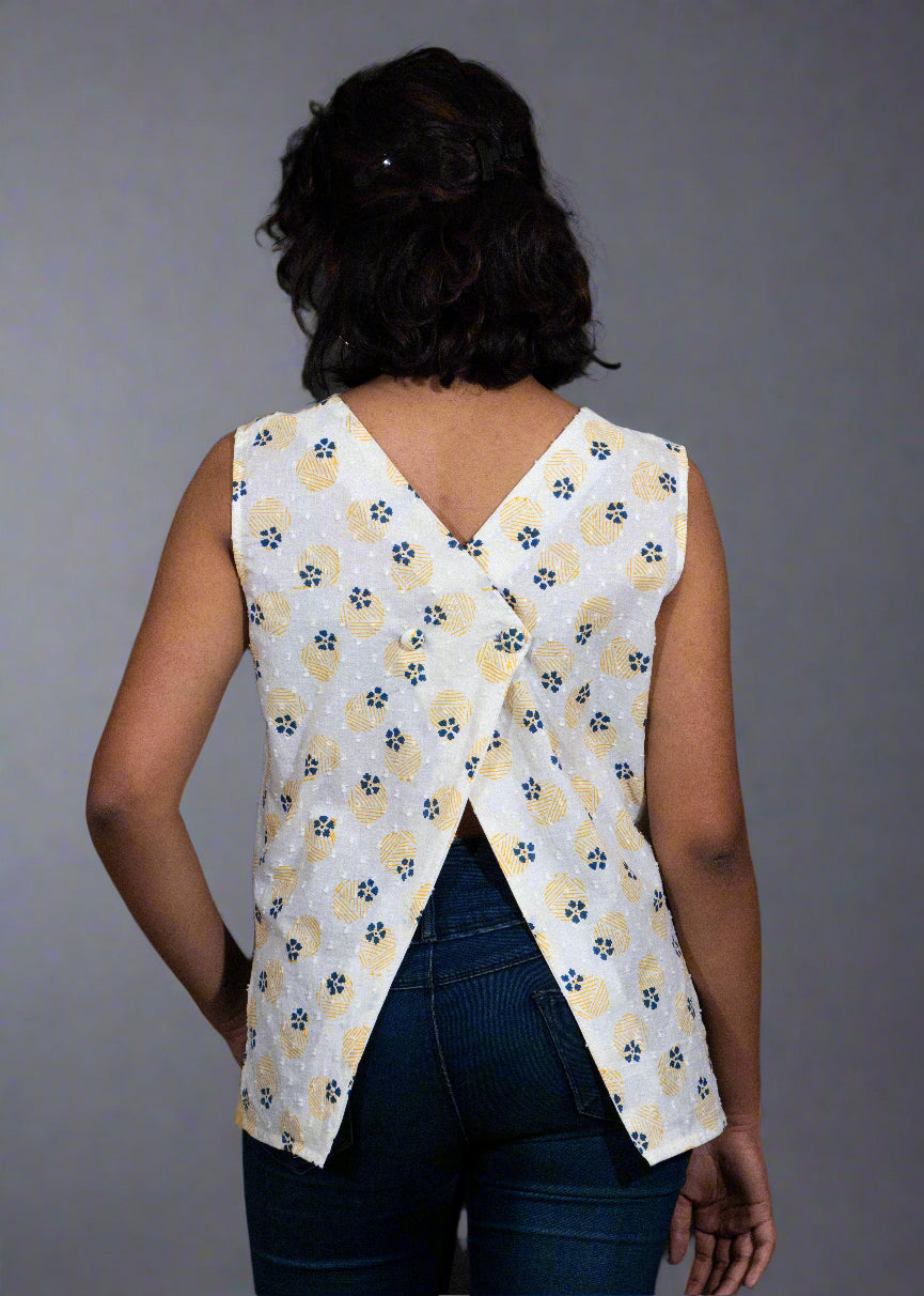 Person wearing a sleeveless floral top with a criss-cross back design on a black background