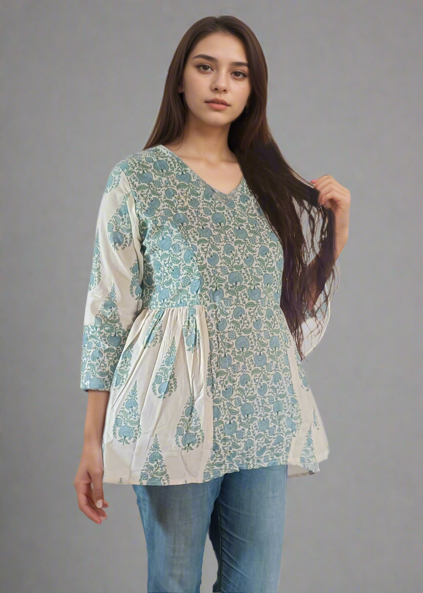 Woman wearing a patterned flroral paisley top and jeans on a plain background
