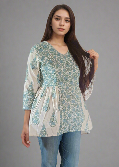 Woman wearing a patterned flroral paisley top and jeans on a plain background