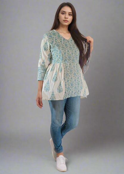 Woman wearing a floral flared tunic top and blue jeans against a plain background