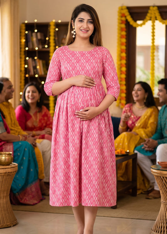 A pregnant woman stands in a decorated indoor room wearing a pink patterned maternity dress.