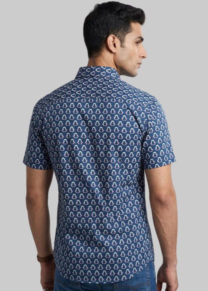 Man wearing a jaipuri cotton blue penguine patterned shirt and jeans on a gray background