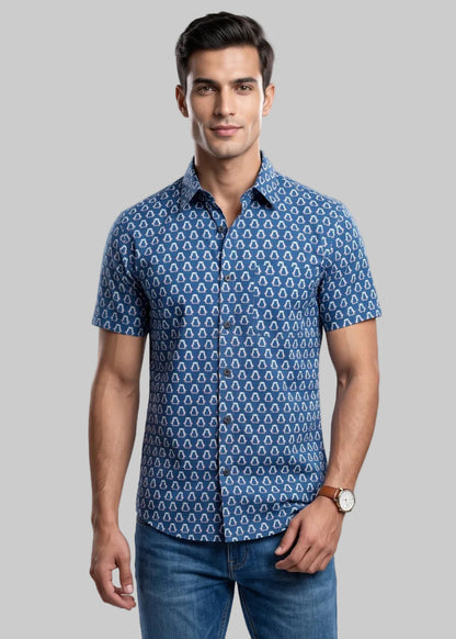 Man wearing a jaipuri cotton blue penguine patterned shirt and jeans on a gray background