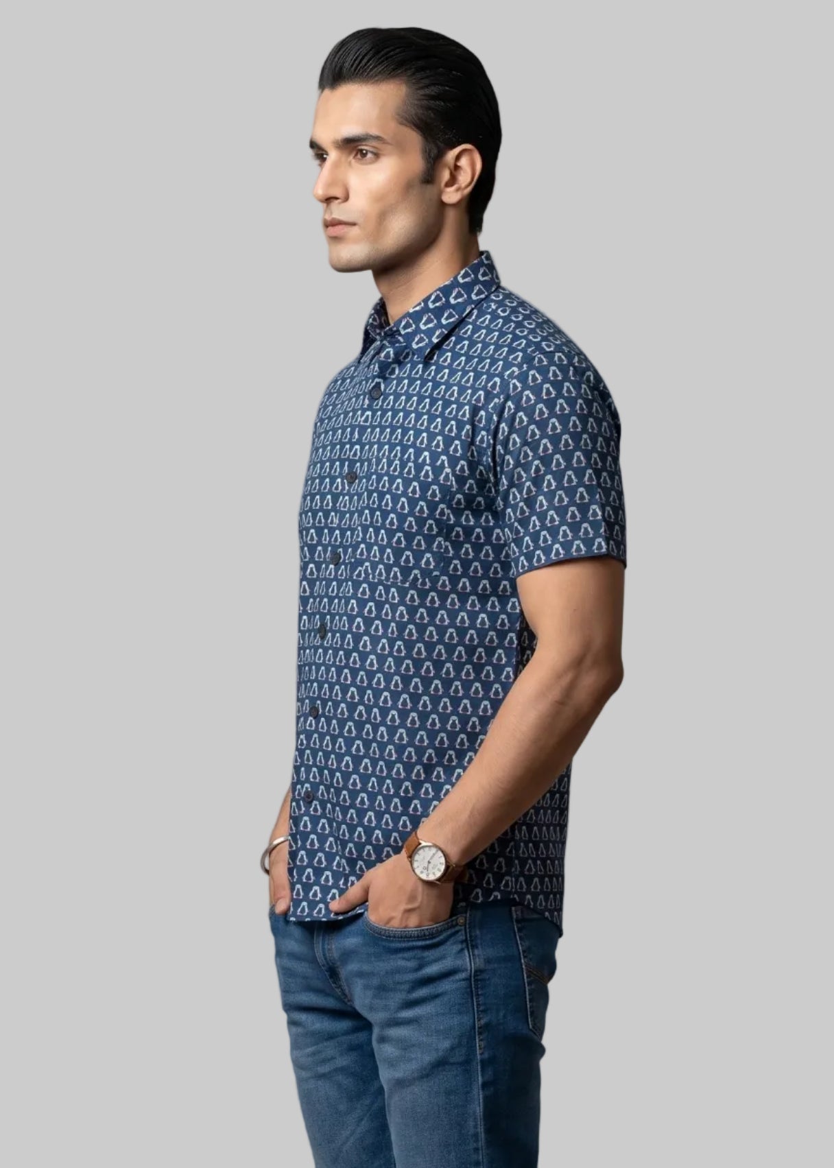 Man wearing a jaipuri cotton blue penguine patterned shirt and jeans on a gray background