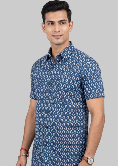 Man wearing a jaipuri cotton blue penguine patterned shirt and jeans on a gray background