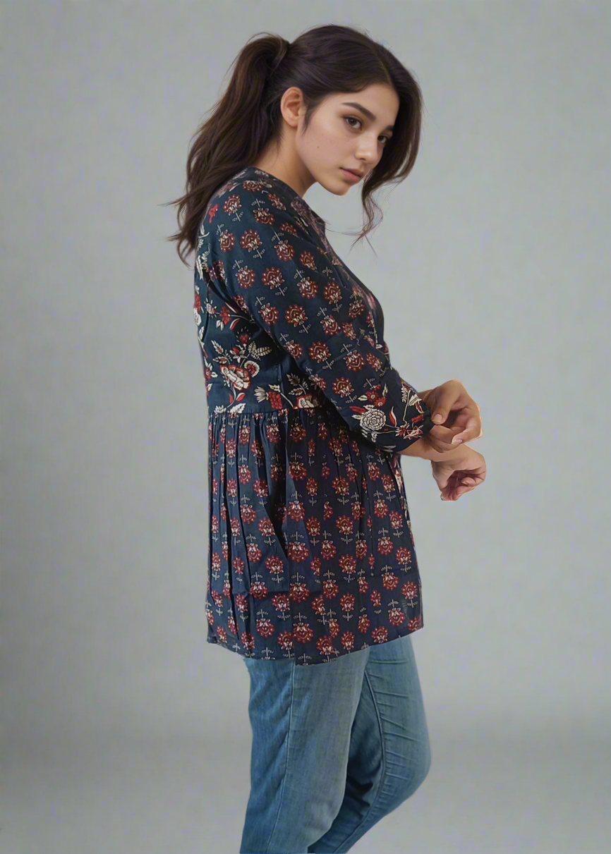 Woman wearing a floral dress and blue jeans with white sneakers on a plain background