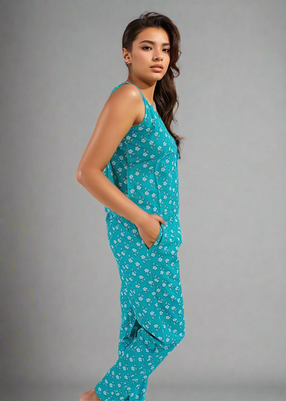 Woman wearing a teal pajama set with white floral pattern on a gray background