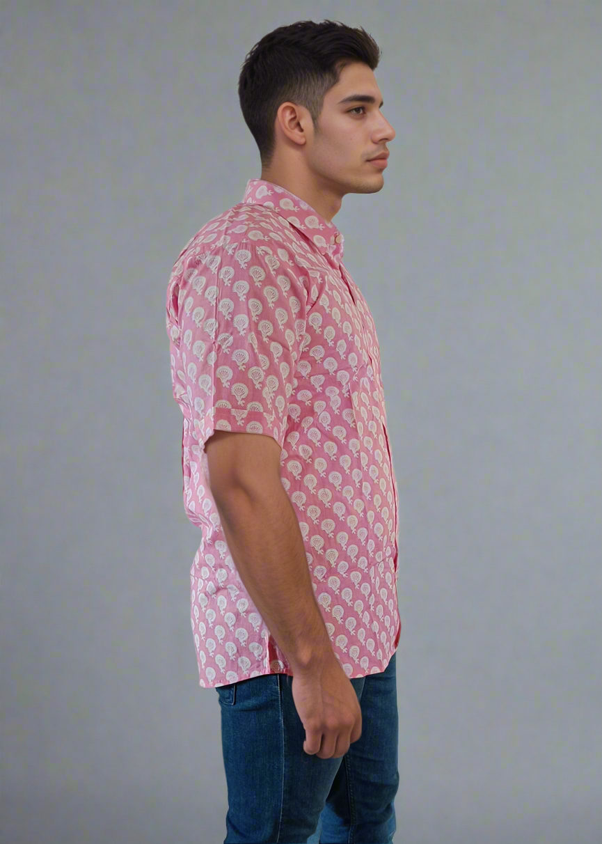 Man wearing a pink patterned shirt and blue jeans on a plain background