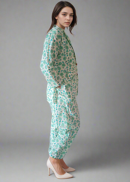 Woman wearing a green and white patterned co-ord suit on a plain background