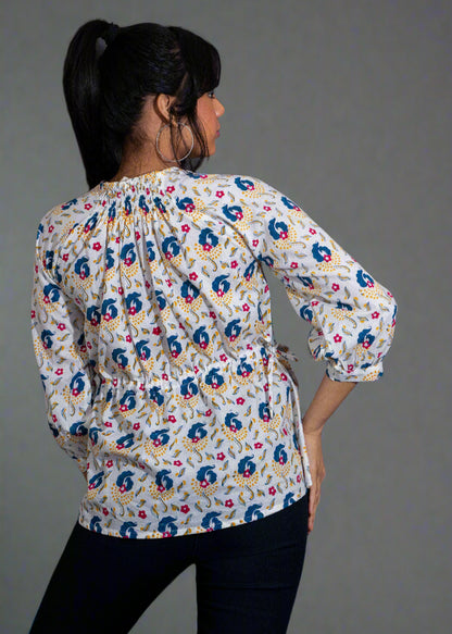 Woman wearing a hand block floral paisley blouse against a dark background